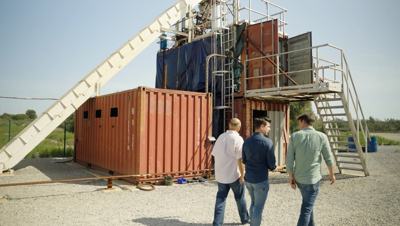 Site industriel d'une PME : containers de production et passerelle technique, équipe technique en visite